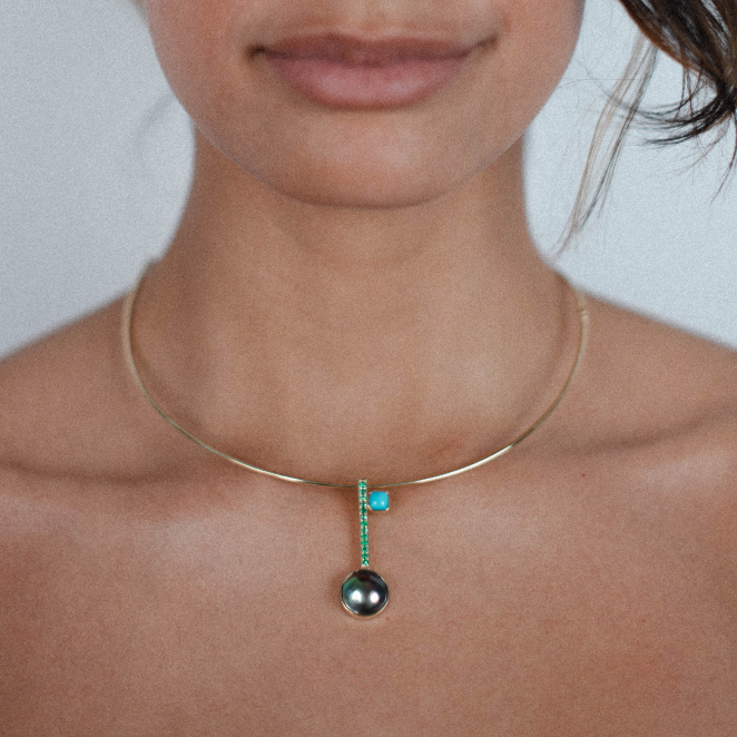 Model wearing the Clé N.5 in 18K yellow gold with black pearl, emeralds and turquoise, paired with the Essential gold collar