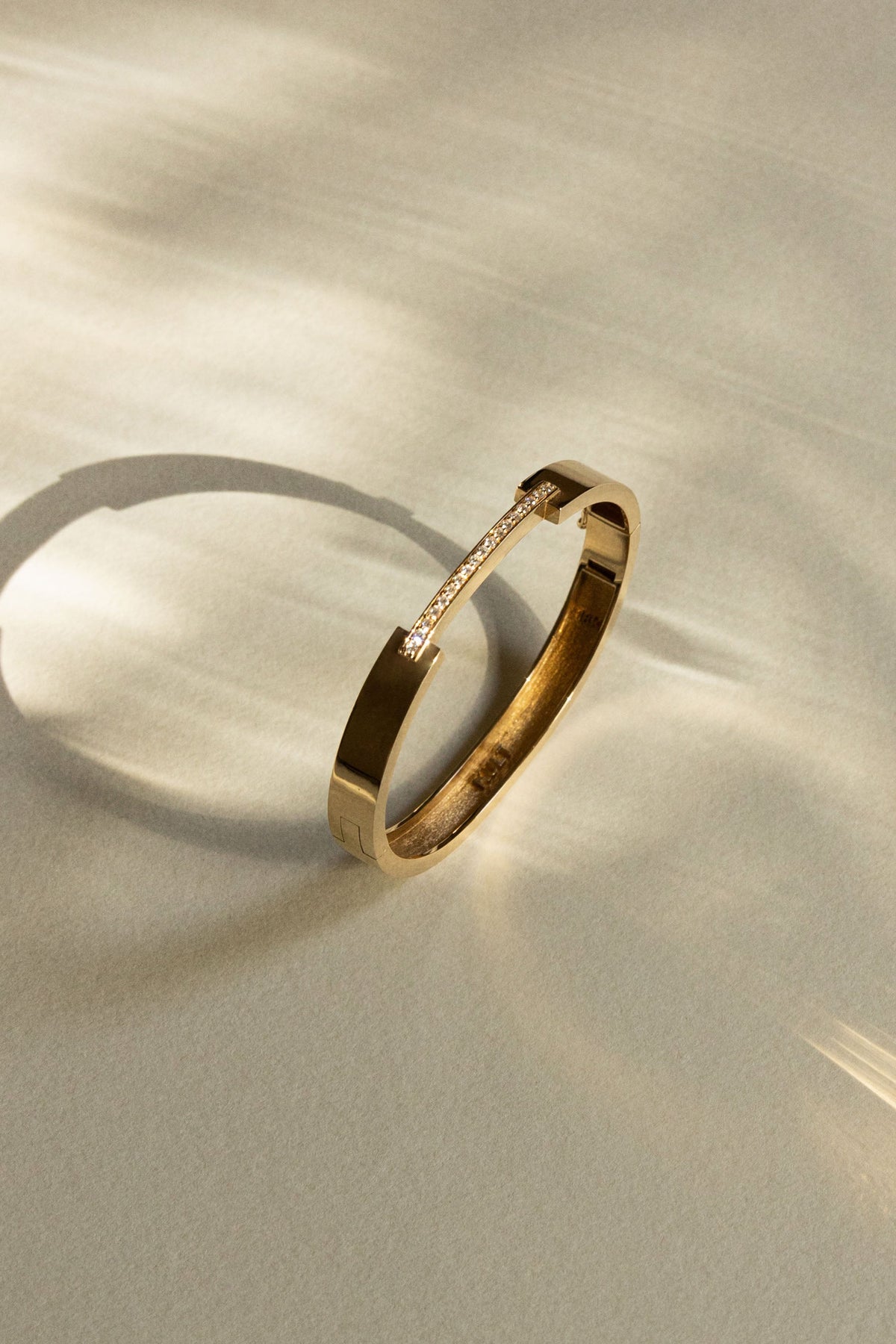 Gold bangle with a pavé diamond bar detail, photographed in soft sunlight